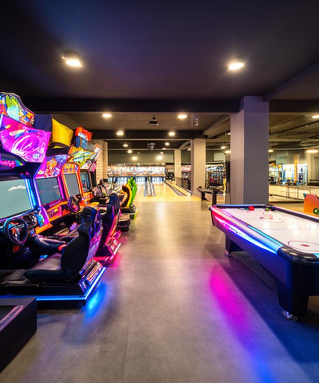 Helle Arcade-Zone im Bowlingcenter mit Rennsimulatoren und Air-Hockey-Tisch